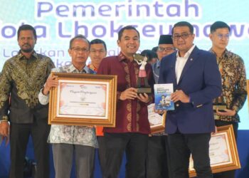 Menteri Ekonomi Kreatif Republik Indonesia, Teuku Riefky Harsya, didampingi oleh Pimpinan Perusahaan Serambi Indonesia, Mohd Din, menyerahkan penghargaan Serambi Ekraf Awards 2025 kepada Wali Kota Lhokseumawe, Sayuti Abubakar