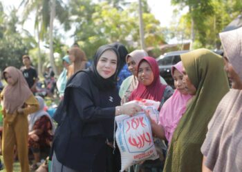 Ketua TP-PKK Kota Lhokseumawe, Ny. Yulinda Sayuti, menyerahkan bantuan paket sembako bagi keluarga prasejahtera hasil sinergi dengan Bank Aceh di Gampong Jambo Timu, Kecamatan Blang Mangat, Kota Lhokseumawe