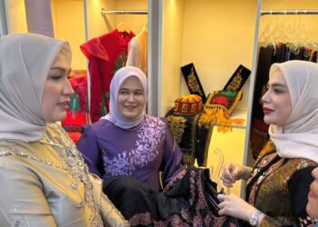 Ketua Dekranasda Lhokseumawe Yulinda Sayuti, memperkenalkan ragam kriya lokal bermotif khas Dheun Bungoeng Sagoe kepada Ketua Dekranasda Aceh Marlina Muzakir di arena Rakerda Dekranasda se-Aceh, Banda Aceh